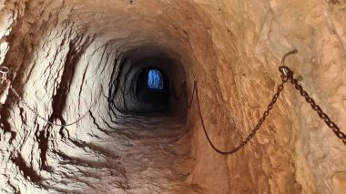Discover the fascinating underground tunnel, adorned with chains and illuminated by a hint of natural light