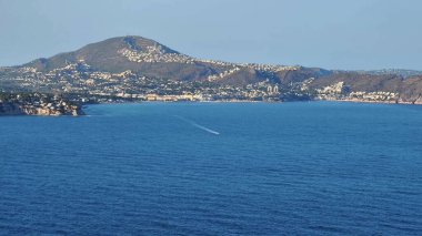 A breathtaking coastal landscape features stunningly majestic mountains alongside serene and calm blue waters