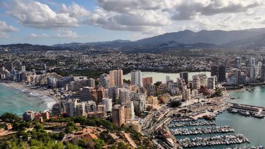 Deniz kıyısındaki marinasıyla birlikte hareketli bir sahil şehrinin canlı güzelliğini gösteren çarpıcı bir hava manzarası.