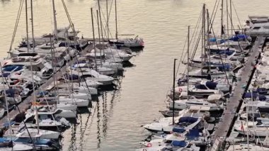 Huzurlu bir marina sahnesi. Güzel lüks yatlar sergileniyor. Şık bir şekilde altın bir günbatımı parıltısının altına demirlenmiş.