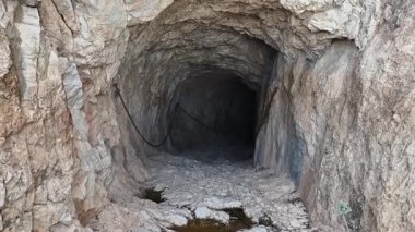 Kayalık duvarlarla karakterize edilmiş engebeli ve gizemli bir tünel ve girişinde küçük, sakin bir su havuzu keşfetmek.