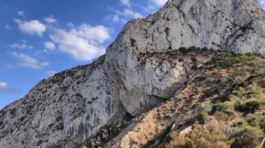 A breathtaking and stunning view of a rocky cliff that is richly detailed against a vibrant blue sky filled with clouds
