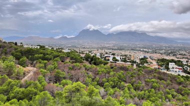 A breathtaking panoramic view showcasing majestic mountains and lush greenery towering over a lively urban landscape