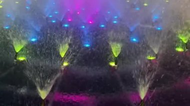 Renkli bir fıskiyenin büyüleyici bir görüntüsü, canlı ışıklar, gece manzarasının güzelliğini arttırıyor.