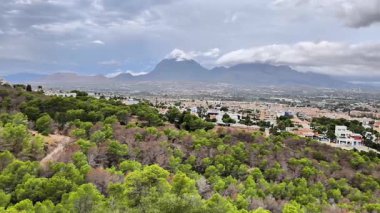 A breathtaking panoramic view showcasing majestic mountains and lush greenery towering over a lively urban landscape