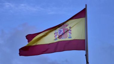 İspanyol bayrağının parlak mavi bir arkaplana gururla el salladığı büyüleyici güzel bir fotoğraf.