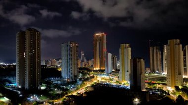 Büyüleyici ve çarpıcı bir gece manzarası parlak aydınlatılmış gökdelenleri karanlık gökyüzüne karşı sergiliyor