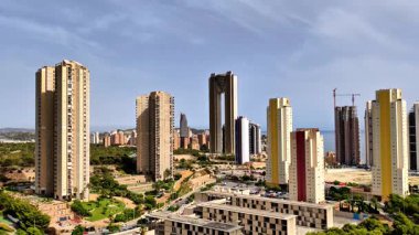 Açık mavi gökyüzüne karşı inşa edilmiş nefes kesici ve çarpıcı bir şehir manzarası modern mimari binalar.