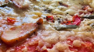 Lezzetli bir pizzanın, lezzetli malzemelerini ve erimiş peynirini ön plana çıkaran cezbedici zoodin görüntüsü.