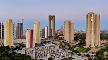 Nefes kesen şehir manzarası yüksek binalar, canlı yeşillikler ve çarpıcı bir gökyüzü.