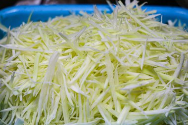 Tay Som Tam salatası için taze ve çıtır çıtır yeşil papaya tepsisi. Sokak yemekleri, aşçılık turizmi ve otantik Tayland mutfağında popülerdir..