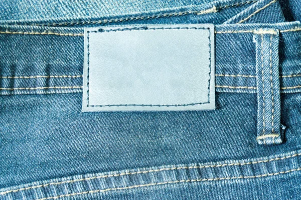 Leather label sewed on jeans. leather label on worn blue denim with orange seams, good for background.