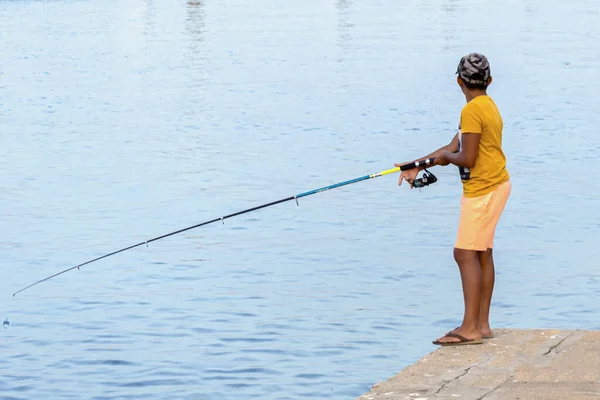 在西班牙南部海岸一个小渔港的码头上钓鱼的一个男孩 免版税图库照片