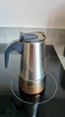 Mutfakta ev konforu, ocakta metal bir kahve demliği kahve yapıyor.