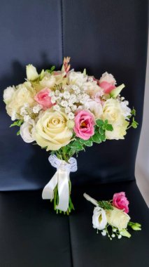 Bir buket gül. Yuvarlak, narin bir düğün buketi, sapları ve çiçekli pembe ve beyaz gül renginde, Eustoma, gypthe ve yeşillik siyah bir sandalyede.. 