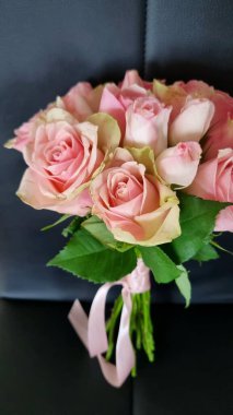 hediye demeti pembe güller siyah bir sandalyede pembe kurdeleli, çiçekçi dükkânı konsepti