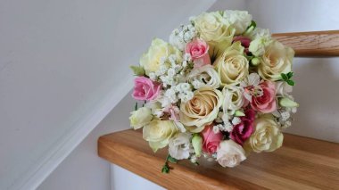 İç kısımda bir düğün buketi. Gül, östoma, çingene ve yeşillikten yapılmış pembe ve beyaz renklerde narin bir düğün buketi..