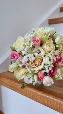 İç kısımda bir düğün buketi. Gül, östoma, çingene ve yeşillikten yapılmış pembe ve beyaz renklerde narin bir düğün buketi..