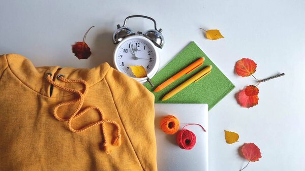 Осеннее обучение тема с оранжевым капюшоном, ноутбук, ноутбук и ручки, осенние листья, нити и часы на белом фоне. Предпосылки для обучения или бизнеса в осеннее время.