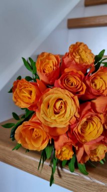 Yeşillik ve ahşap merdivenlerde beyaz kurdeleli turuncu güller.