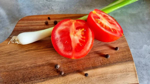 Düzgün beslenme konsepti, evde pişirme, ev yemeği, kesilmiş domates, soğan ve biberli tabak, mutfakta gri bir masa..