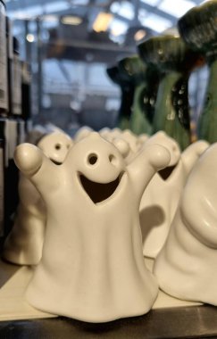 Cadılar Bayramı temalı dekor, beyaz seramik hayaletler iç dekorasyon için farklı pozlar, rafta beyaz seramik hayaletler..