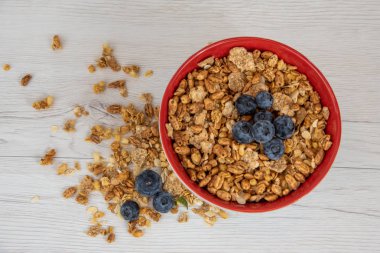 Bir kırmızı kase tam granola Beyaz ahşap masa, üstten görünüm üzerinde çilek ile