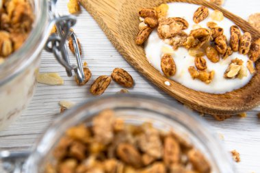 Granola, ahşap ile bir kavanoz dolu kaşık Beyaz ahşap masa, yakın-up, seçici odak whit granola
