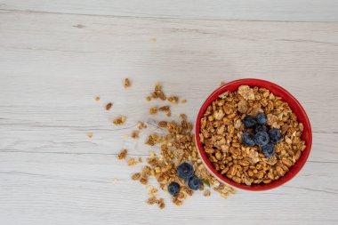 Bir kırmızı kase tam granola Beyaz ahşap masa, üstten görünüm üzerinde çilek ile