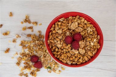 Bir kırmızı kase tam granola Beyaz ahşap masa, üstten görünüm üzerinde çilek ile