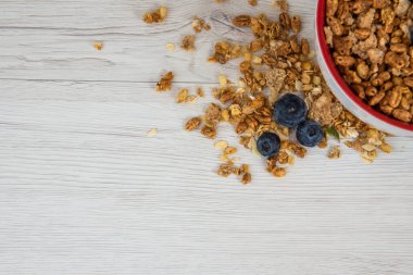 Tam bir kaşık Beyaz ahşap masa, üstten görünüm, kopya alanı ile kırmızı bir kase, granola