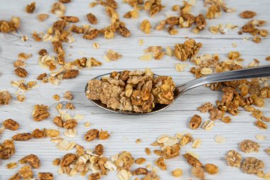 Beyaz ahşap masa üzerinde granola dolu kaşık