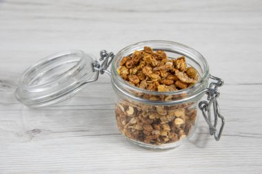 Beyaz ahşap masa üzerinde granola dolu kavanoz