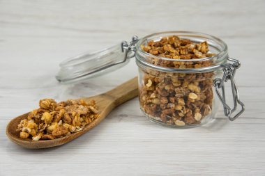 Granola dolu ve wow kaşıkla granola Beyaz ahşap masa üzerinde dolu kavanoz
