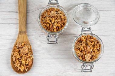 İki granola ve beyaz ahşap masa, üstten görünüm üzerinde bir tahta kaşık tam whit granola dolu kavanozları