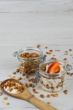 Granola ve yoğurt, tahta kaşık whit granola ve kayısı Beyaz ahşap masa üzerinde dolu bir kavanoz