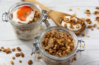 Granola, ahşap ile bir kavanoz dolu kaşık Beyaz ahşap masa, yakın-up, seçici odak whit granola