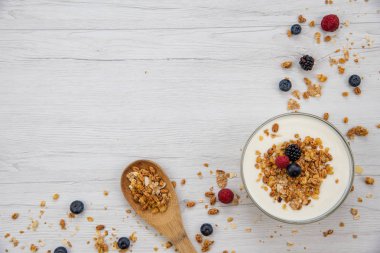 Kase Yoğurt granola ve taze meyveler ve tahta kaşık tam whit granola Beyaz ahşap masa, arka plan, üstten görünüm, kopya alanı ile