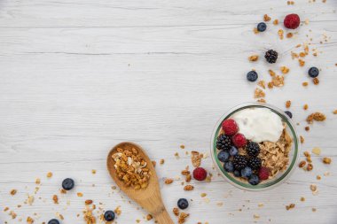 Kase Yoğurt granola ve taze meyveler ve tahta kaşık tam whit granola Beyaz ahşap masa, arka plan, üstten görünüm, kopya alanı ile