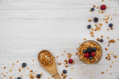 Granola ve taze meyveler ve tahta kaşık tam whit granola Beyaz ahşap masa, arka plan, üstten görünüm, kopya alanı ile bir kase