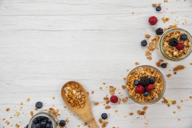Kavanoz granola ve taze meyveleri ve tahta kaşık tam whit granola üzerinde beyaz ahşap masa, arka plan, üstten görünüm, tam alanı Kopyala