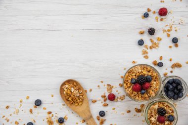 Kavanoz granola ve taze meyveleri ve tahta kaşık tam whit granola üzerinde beyaz ahşap masa, arka plan, üstten görünüm, tam alanı Kopyala