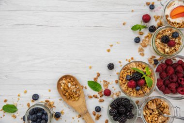 Kavanoz granola, yoğurt ve taze meyveleri ve tahta kaşık tam whit granola Beyaz ahşap masa, arka plan, üstten görünüm, kopya alanı ile tam