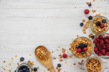 Kavanoz granola ve taze meyveleri ve tahta kaşık tam whit granola üzerinde beyaz ahşap masa, arka plan, üstten görünüm, tam alanı Kopyala