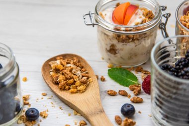 Kavanoz granola, yoğurt ve taze meyveleri ve tahta kaşık tam whit granola, yakın çekim, seçici odak ile tam