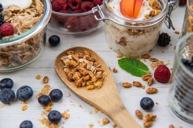Kavanoz granola, yoğurt ve taze meyveleri ve tahta kaşık tam whit granola, yakın çekim, seçici odak ile tam
