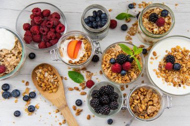 Granola, yoğurt ve taze meyveleri ve tahta kaşık tam whit granola, üstten görünüm seçici odak ile dolu kavanoz