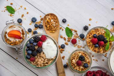 Granola, yoğurt ve taze meyveleri ve tahta kaşık tam whit granola, üstten görünüm seçici odak ile dolu kavanoz