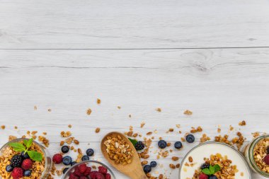 Kavanoz granola, yoğurt ve taze meyveleri ve tahta kaşık tam whit granola Beyaz ahşap masa, üstten görünüm, seçici odak, kopya alanı ile tam