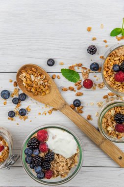 Granola, yoğurt ve taze meyveleri ve tahta kaşık tam whit granola, üstten görünüm seçici odak ile dolu kavanoz